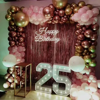 Celebrating a 25th birthday in style with a rose gold sequin backdrop, a matching balloon frame, and large '25' marquee numbers. It's a chic and modern setup perfect for photos.