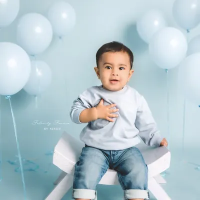 A classic sitter session portrait with a simple, clean background. This little boy's sweet expression and the soft blue tones create a timeless and heartwarming image.