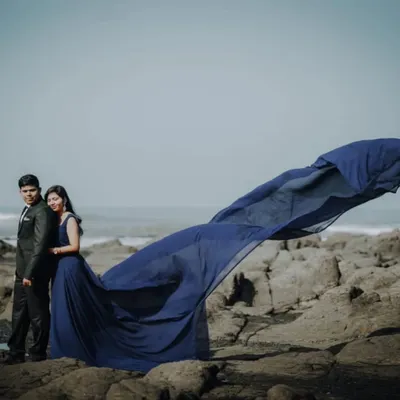 This classic navy blue gown with a flowing trail is one of our most popular rentals for pre-wedding shoots. It creates a stunning silhouette against the rocky beach and waves.