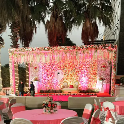 A spectacular floral stage is the heart of a beautiful wedding reception. This setup features a dense wall of fresh pink and white flowers, creating a truly romantic and unforgettable backdrop.