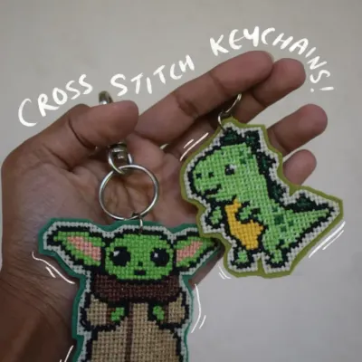 Here are two of my favorite cross-stitch keychains. I hand-stitch each one to look like pixel art, featuring a tiny Baby Yoda and a cute green dinosaur. They come with a sturdy clasp, perfect for adding some personality to your keys or bag.