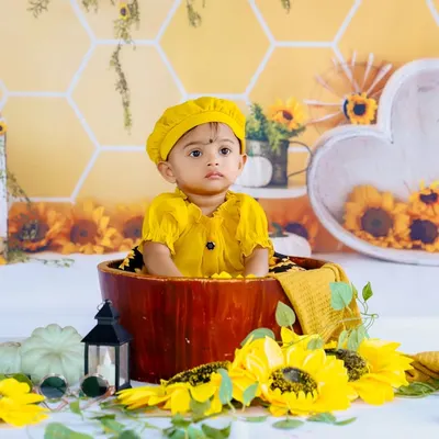 Our sunflower theme is perfect for a bright and cheerful photoshoot. This little one looks adorable in a yellow outfit, sitting in a wooden bucket surrounded by sunflowers.