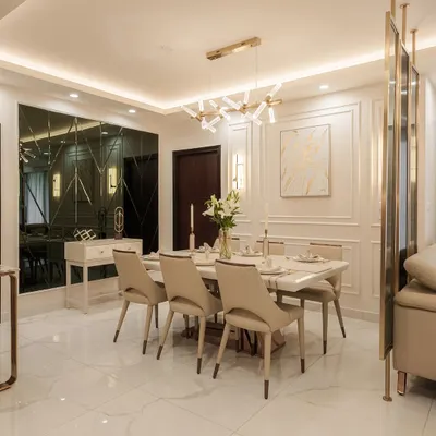 This elegant dining area at DNR Arista features a stunning marble-top table and comfortable upholstered chairs, set against a backdrop of classic wall molding. The modern chandelier and reflective wall partition add layers of light and luxury, creating an ideal setting for both intimate meals and grand celebrations.