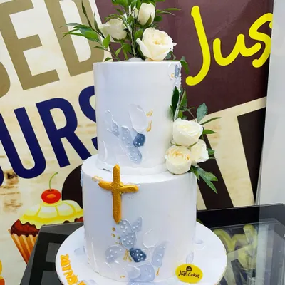 A stunning 5kg two-tiered Baptism cake in white, decorated with delicate fresh roses, subtle blue and grey painted details, and a golden cross.