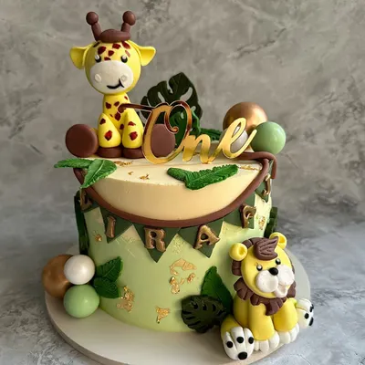 A wild first birthday adventure! This jungle-themed cake features hand-modeled fondant animals, including a friendly giraffe and lion, set against a backdrop of edible leaves and gold accents.