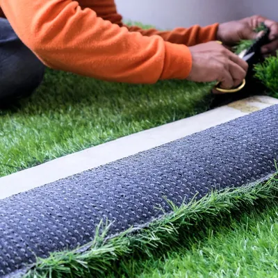 Our installation process involves meticulous attention to detail. Here, a member of our team is precisely cutting the turf to ensure tight, invisible seams for a smooth and uniform final surface.