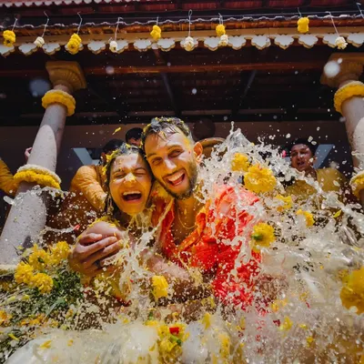 The peak of Haldi fun. This incredible action shot captures the couple's pure joy as they are drenched with water and flower petals, a perfect moment of celebration and togetherness.
