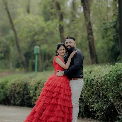A classic portrait from an engagement shoot in a lush Pune garden. The woman's striking red gown and the couple's confident pose create a timeless and elegant image, showcasing a more formal and styled approach to pre-wedding photography.