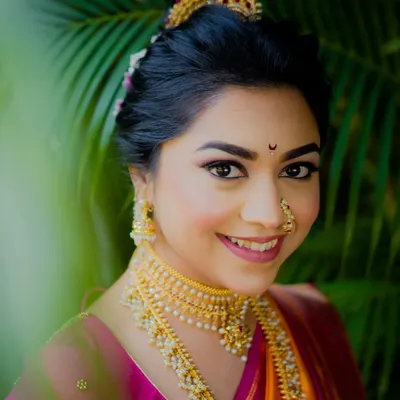 A close-up of Sneha's quintessential Maharashtrian bride look. She wanted a clean skin finish with bold, glittery eyes. The result was a beautiful balance that celebrated her features and her roots, complete with a traditional khopa hairstyle.