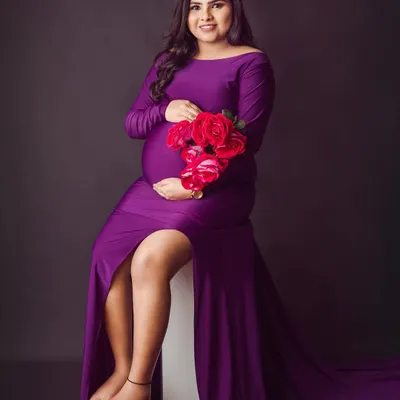 A bold and beautiful solo maternity portrait. The rich purple gown with its thigh-high slit and the pop of red roses create a truly glamorous and confident look.