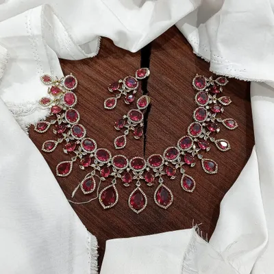 A stunning AD necklace set laid out to show its full design. This piece is available in multiple vibrant colors like ruby red, emerald green, pastel blue, and sapphire blue, featuring teardrop-shaped stones.