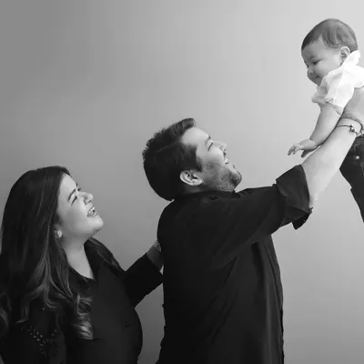 A moment of pure joy and connection as a father lifts his baby high in the air, with mom looking on lovingly. These black and white family portraits are timeless.