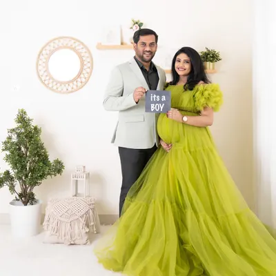 A happy couple announces "It's a boy!" during their studio maternity session. The mother-to-be looks stunning in a vibrant green tulle gown I provided for the shoot.