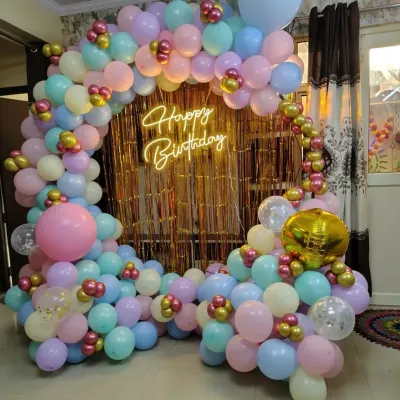 A colorful pastel balloon ring with a gold fringe backdrop and a "Happy Birthday" neon sign, perfect for a cheerful home party.