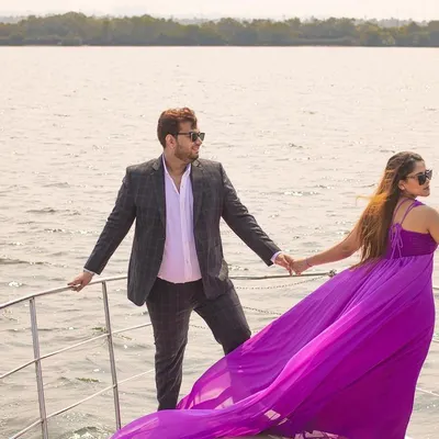 A stunning shot of the couple on a private yacht in Goa, with the bride's vibrant purple gown flowing in the wind. This is the essence of a luxurious destination pre-wedding shoot.