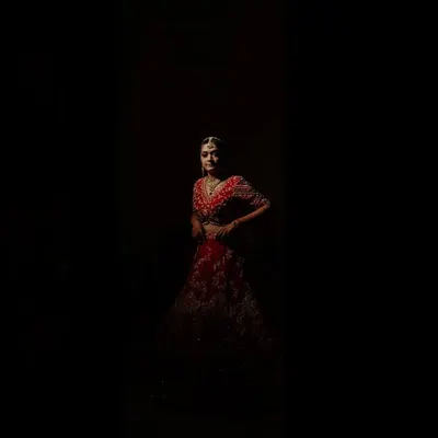 A dramatic and artistic bridal portrait of Anjali. The use of shadow and light creates a powerful image that highlights her beauty and the richness of her red lehenga.