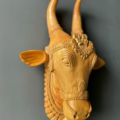 A hand-carved wooden bull head, inspired by the festival traditions of Kerala. The natural wood finish and intricate details make it a subtle yet powerful piece of wall decor that tells a story of cultural heritage.