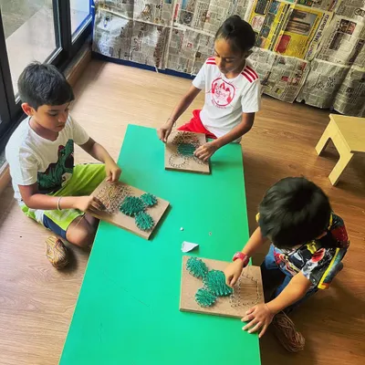 Older campers focus on a detailed string art project. This activity helps develop fine motor skills, patience, and artistic expression as they create cactus designs.
