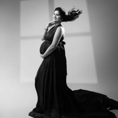 Unveiling the elegance and grace of motherhood in a timeless monochrome moment. The flowing gown and serene smile create a work of art that transcends time.