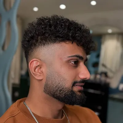 This is what we do best. A perfect high fade blended into natural curls, finished with a sharp beard line-up. It's a modern, clean, and stylish look.