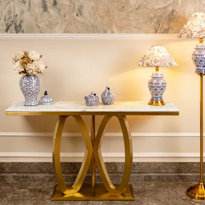 This console table features a white marble top and a striking gold stainless steel base with an interlocking oval design. It's a glamorous and modern piece, perfect for an entryway or living room.