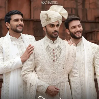 A professional editorial shoot featuring natural grooming for men. The focus is on clean skin, defined brows, and neat hair to create a polished look for these traditional sherwanis.