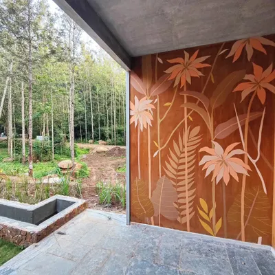 This tropical mural on a warm, terracotta-colored wall is designed to complement the surrounding forest, blurring the line between inside and out.