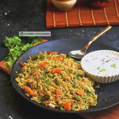 Our Vangibath is a flavorful and aromatic rice preparation from Karnataka, made with eggplant, a special spice powder, and fresh vegetables. It is served here with a cooling side of vegetable raita.