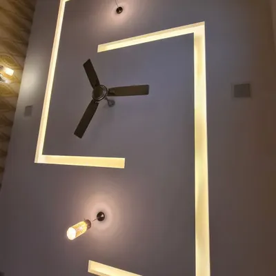 A modern false ceiling with a dynamic, asymmetrical geometric design. Integrated LED strip lighting traces the sharp angles, while two minimalist pendant lights provide additional focused light, creating a visually interesting overhead feature.