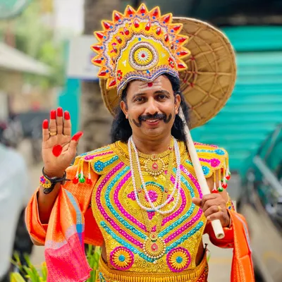 A close up of our Maveli actor, ready to bring joy and blessings to your celebration. The costume includes the iconic crown, ornate chest piece, and traditional umbrella, or olakkuda.