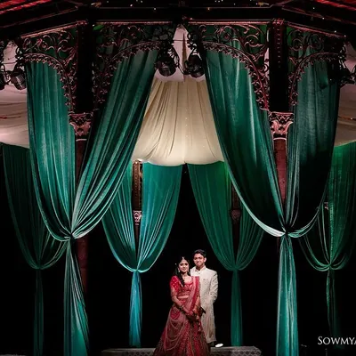 A grand, dramatic portrait of a couple standing amidst elegant green drapes. This shot highlights the beautiful decor and creates a regal, cinematic feel for their pre-wedding shoot.