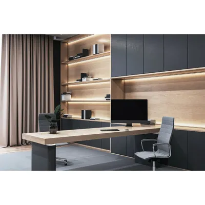 A sleek and modern home office with a minimalist aesthetic. The design features a long floating desk, integrated shelving with backlighting, and dark, handleless cabinetry for a clean and professional look.