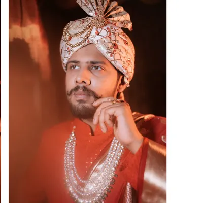 A stylish, low-angle portrait of the groom, highlighting his majestic 'pheta' and multi-layered pearl necklace.