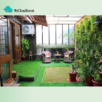 This semi-covered terrace is a complete outdoor room. I combined soft artificial grass with a wicker seating area, a lush vertical garden on one wall, and a thatched roof element to create a cozy, protected space that can be enjoyed in any weather.