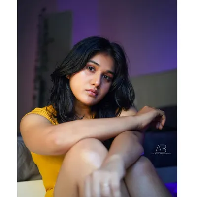 An intimate, moody portrait. The purple ambient light and soft shadows create a cinematic feel, drawing all the attention to her expressive gaze. This is a perfect example of an indoor, story-driven shot.