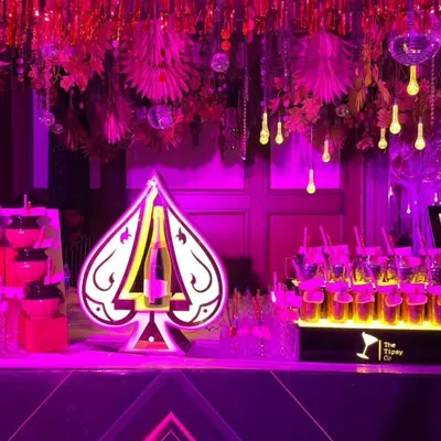 For this event, we created a glamorous bar setup featuring a custom 'Ace of Spades' light installation. The vibrant pink lighting and disco ball decor transformed the space into a high-energy party zone.