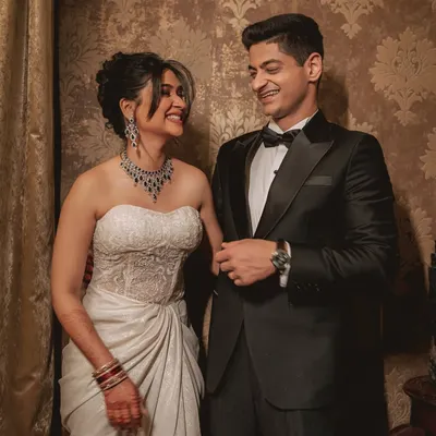 A beautiful, classic portrait of a couple in formal evening wear. Their shared glance and smiles speak volumes, captured against an elegant, patterned backdrop at Villa Kasu.