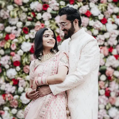 A beautiful portrait of a couple in coordinated pastel outfits against a floral backdrop. This image is all about elegance, showcasing the intricate details of their traditional wear and their loving gaze.