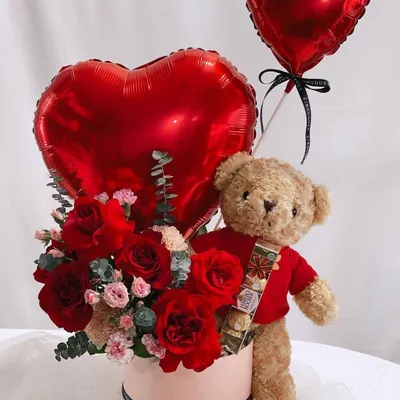 A classic Valentine's Day gift. This hamper comes with a teddy bear holding a bar of chocolate, a box of red roses, and heart shaped foil balloons.