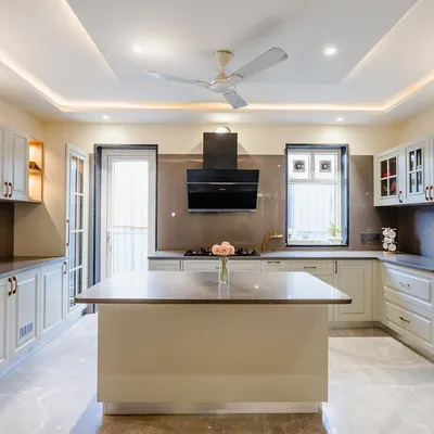 This island kitchen is a masterpiece of modern design. The off-white shaker-style cabinets give it a timeless, classic feel, while the large island provides ample workspace and casual seating. The space is bright and airy, thanks to the large window and uPVC door.
