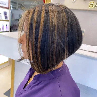 A chic and trendy angled bob haircut. We added bold blonde highlights to make the sharp lines of the cut stand out.