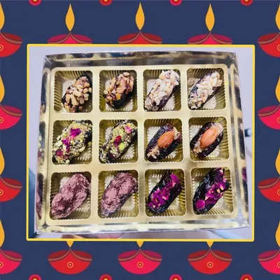 A festive box of my vegan stuffed dates, perfect for gifting. This assortment shows a variety of toppings, including chopped nuts, rose petals, and pistachios, all beautifully arranged.