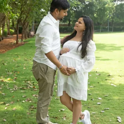 A sweet and casual moment between a couple in a beautiful green park. Their coordinated white outfits and happy smiles create a fresh and natural portrait.