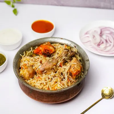 A traditional handi of chicken biryani, served with raita, chutney, and onions on a clean white background, perfect for menus.