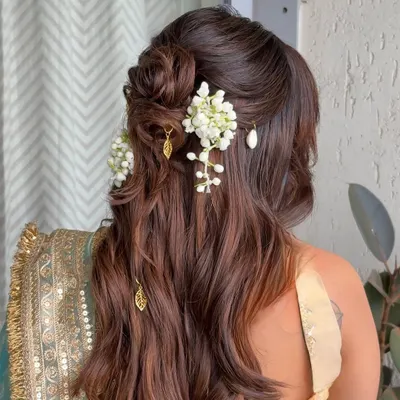 A beautiful half-updo for a baby shower, featuring a messy floral bun with fresh mogra and delicate gold leaf charms hanging from the waves.
