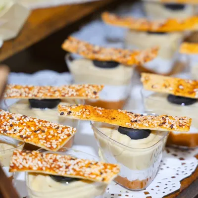 A close-up of our layered hummus dessert cups, topped with a sesame cracker. This dish is a celebration of creativity, where we blend flavors from across continents and serve memories that are thoughtfully presented.