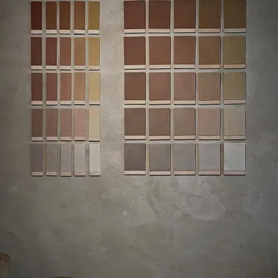 We are always learning and exploring new techniques in earth construction. These sample tiles showcase a range of earth plaster finishes, each with a unique color and texture derived from different soil compositions and pigments.