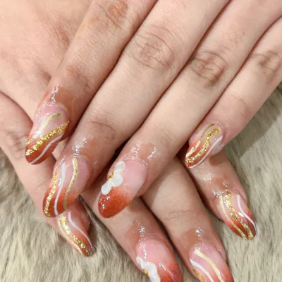 A warm and elegant design featuring a burnt orange ombre effect, accented with delicate white and shimmering gold waves. This is a perfect example of a sophisticated, artistic nail set.