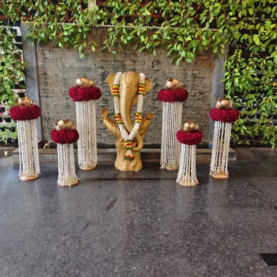 A sacred corner featuring a Ganesha idol, adorned with floral garlands and surrounded by traditional brass lamps and flower arrangements to welcome guests with blessings.