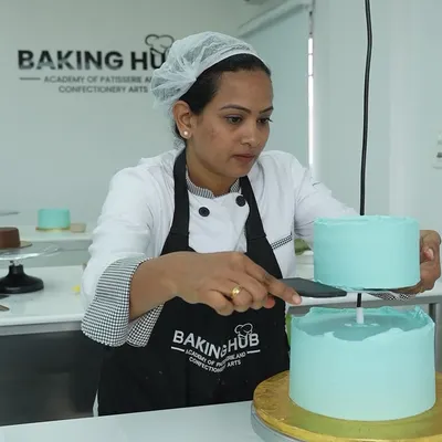 A student carefully stacking a two-tier cake. We teach the crucial techniques for structure and stability, ensuring you can confidently create multi-layered cakes that are both beautiful and secure for transport.